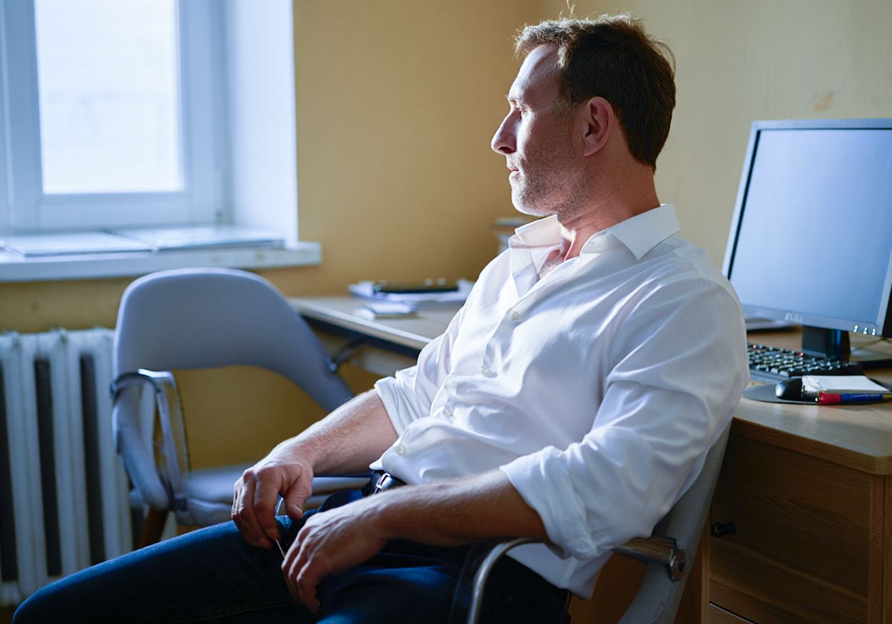 Мужчина апатично сижит на работе